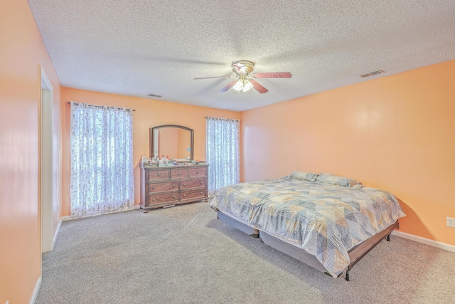 bedroom with multiple windows, light colored carpet, a textured ceiling, and ceiling fan