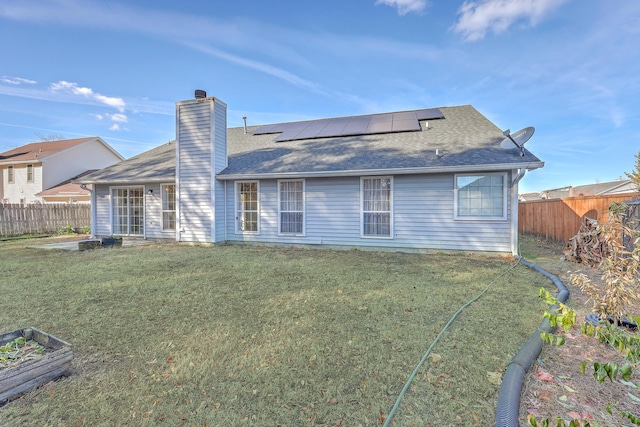 back of house with a yard and solar panels