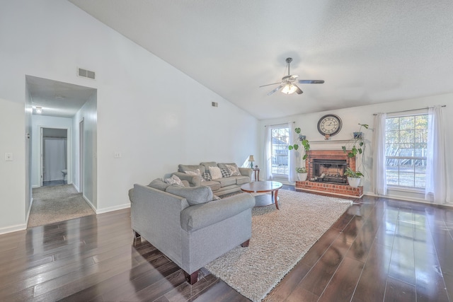 living room with a brick fireplace, a wealth of natural light, high vaulted ceiling, and dark hardwood / wood-style floors