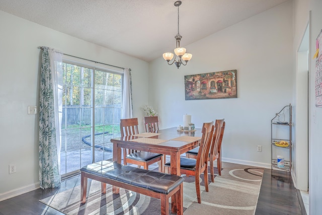 dining room featuring vaulted ceiling, dark wood-type flooring, an inviting chandelier, and a textured ceiling