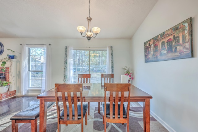 dining space with lofted ceiling, a notable chandelier, wood-type flooring, and a textured ceiling