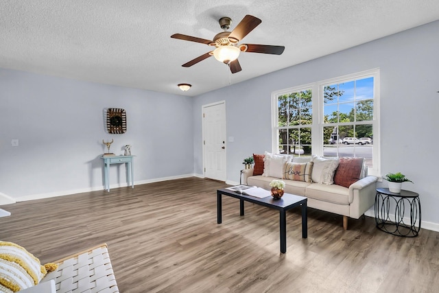 living room with baseboards, a textured ceiling, ceiling fan, and wood finished floors
