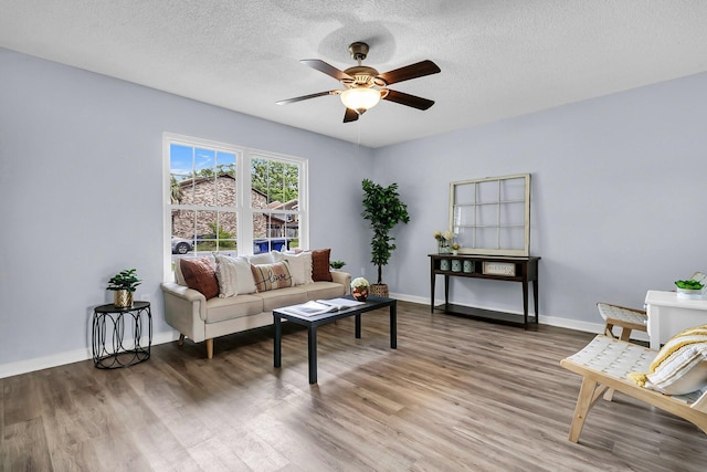 living area with baseboards, a textured ceiling, ceiling fan, and wood finished floors