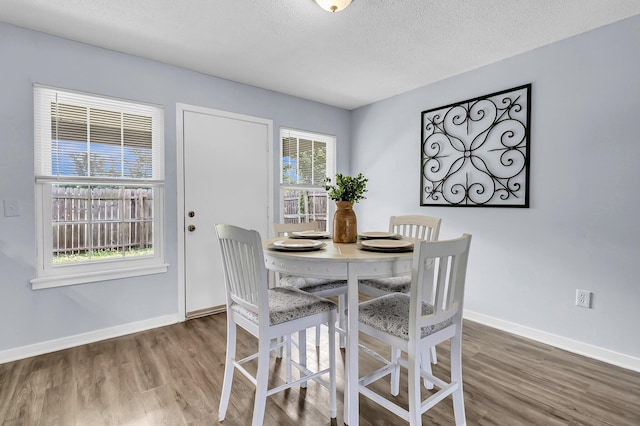 dining room with baseboards, a textured ceiling, and wood finished floors