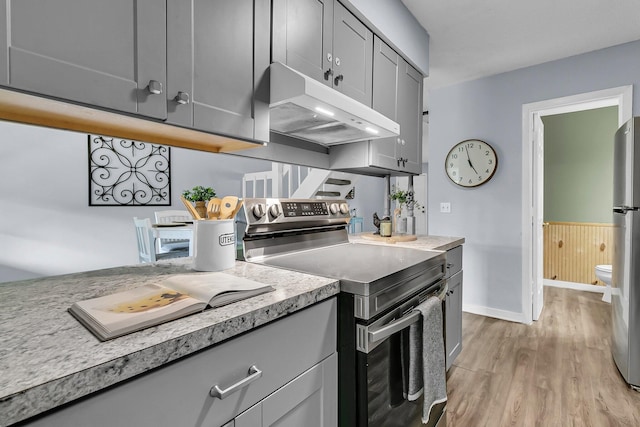 kitchen featuring appliances with stainless steel finishes, light wood-type flooring, gray cabinetry, light countertops, and under cabinet range hood