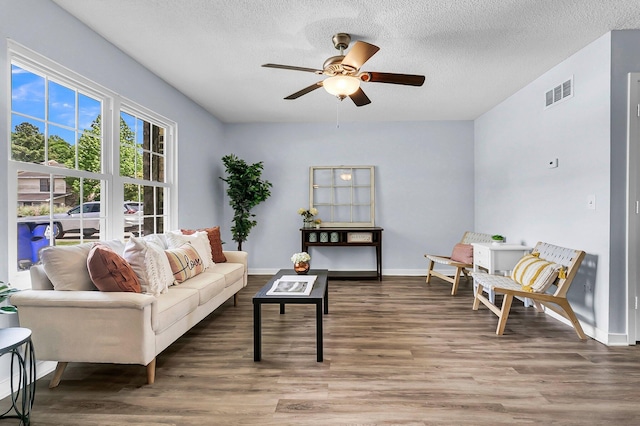 living room featuring a textured ceiling, a ceiling fan, wood finished floors, and visible vents