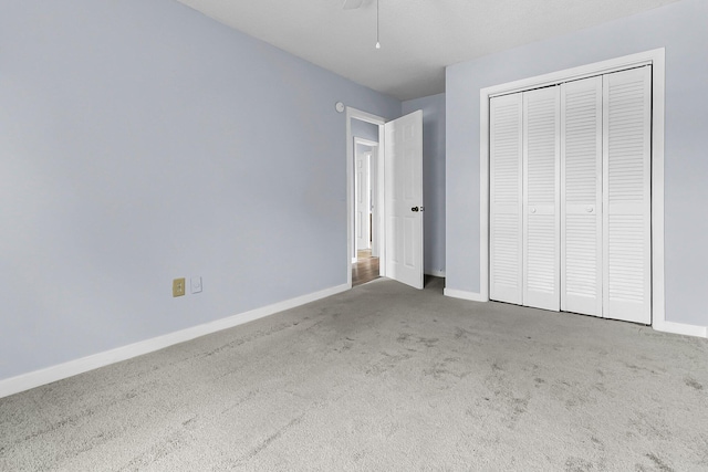 unfurnished bedroom featuring baseboards, carpet flooring, a ceiling fan, and a closet