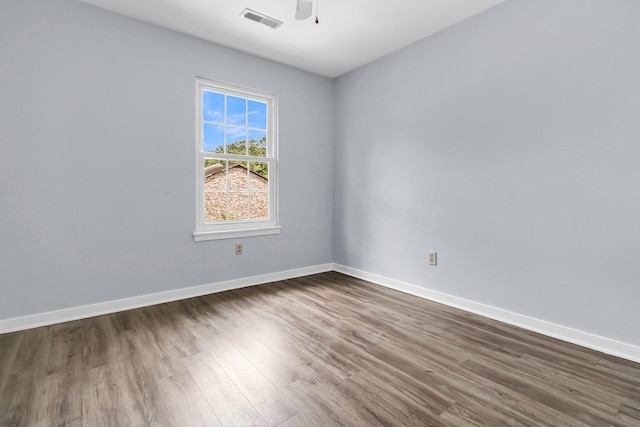 empty room featuring a ceiling fan, baseboards, visible vents, and dark wood finished floors