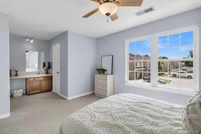 bedroom with visible vents, a ceiling fan, baseboards, light colored carpet, and a sink