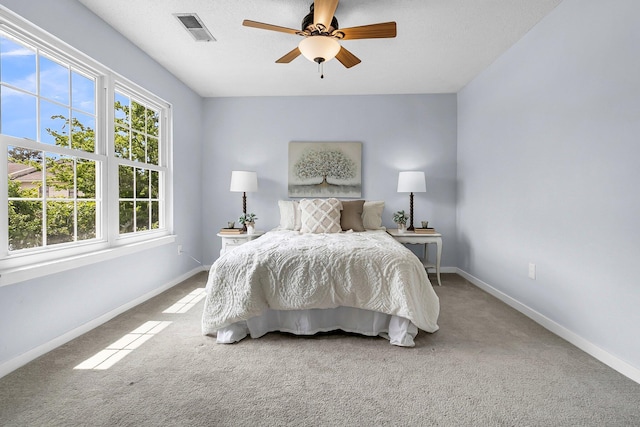 carpeted bedroom featuring baseboards, a ceiling fan, and visible vents