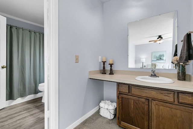 bathroom featuring crown molding, vanity, toilet, a ceiling fan, and curtained shower
