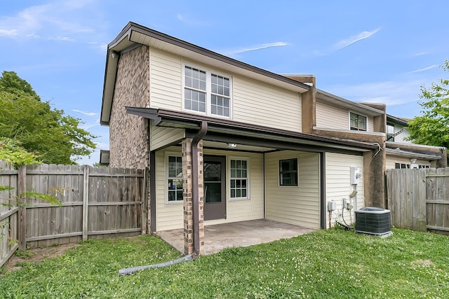 rear view of house with central AC unit, a patio area, a fenced backyard, and a yard