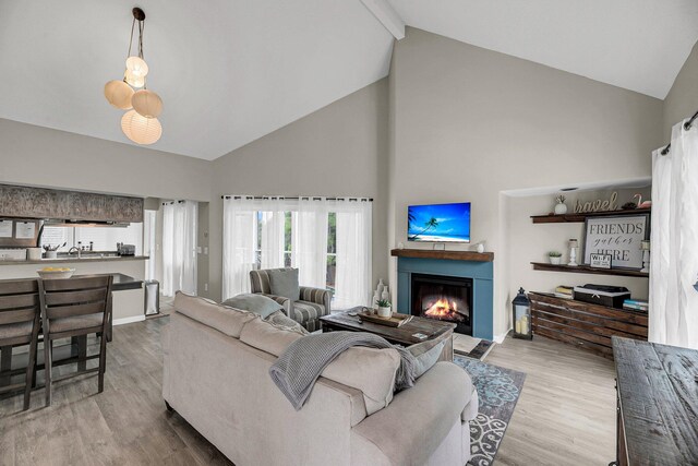 living room featuring high vaulted ceiling, beamed ceiling, and light hardwood / wood-style flooring