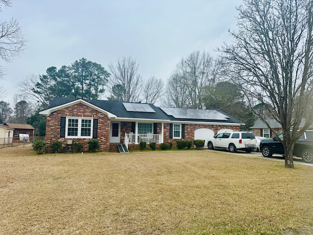 ranch-style home featuring a porch, a front lawn, and solar panels