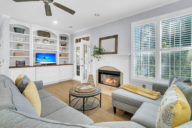 living room with ornamental molding, light hardwood / wood-style floors, ceiling fan, and built in features