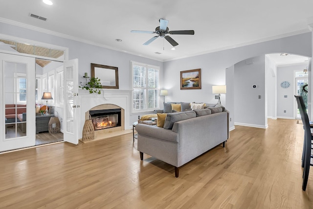 living room with light hardwood / wood-style floors, ceiling fan, and crown molding