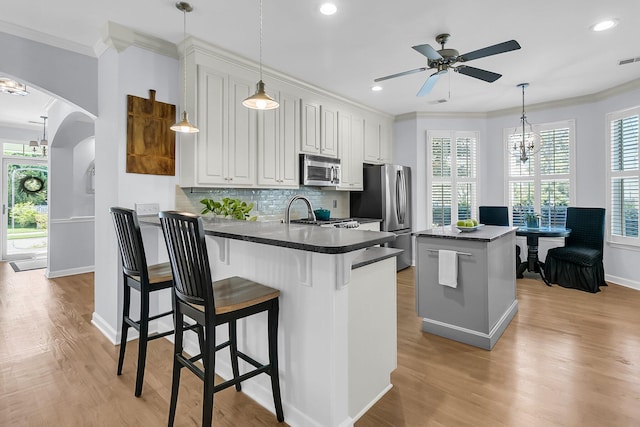 kitchen featuring light hardwood / wood-style floors, appliances with stainless steel finishes, a kitchen breakfast bar, a center island, and white cabinets