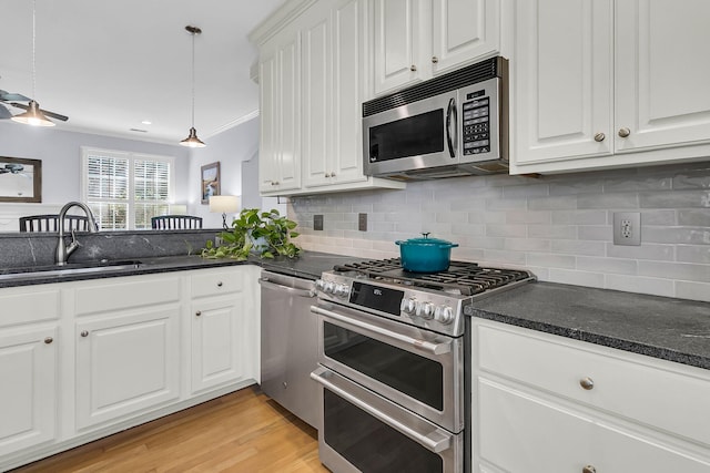 kitchen with stainless steel appliances, white cabinetry, sink, backsplash, and light hardwood / wood-style flooring