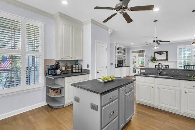 kitchen with a wealth of natural light, white cabinetry, sink, and a kitchen island