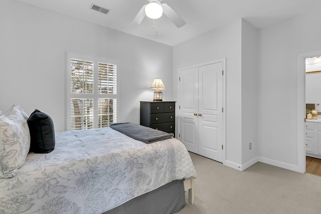 carpeted bedroom with ensuite bathroom, ceiling fan, and a closet