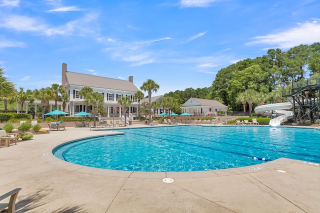 view of swimming pool featuring a water slide and a patio