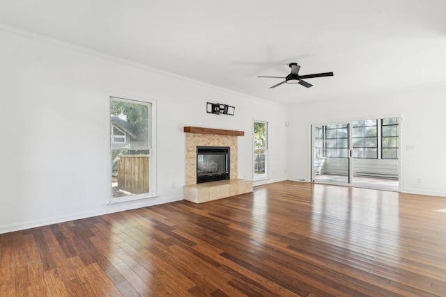 unfurnished living room with a tile fireplace, ceiling fan, wood-type flooring, and ornamental molding