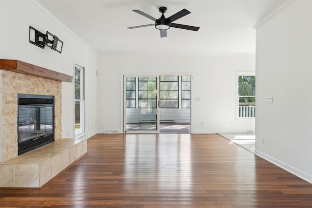 unfurnished living room featuring a tile fireplace, wood-type flooring, ceiling fan, and ornamental molding