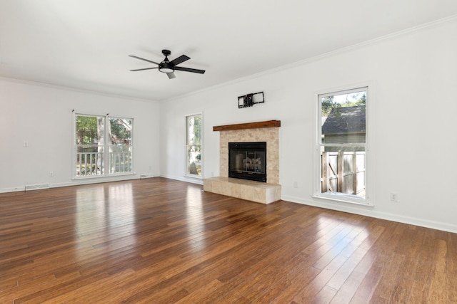 unfurnished living room with ceiling fan, crown molding, dark wood-type flooring, and a tiled fireplace