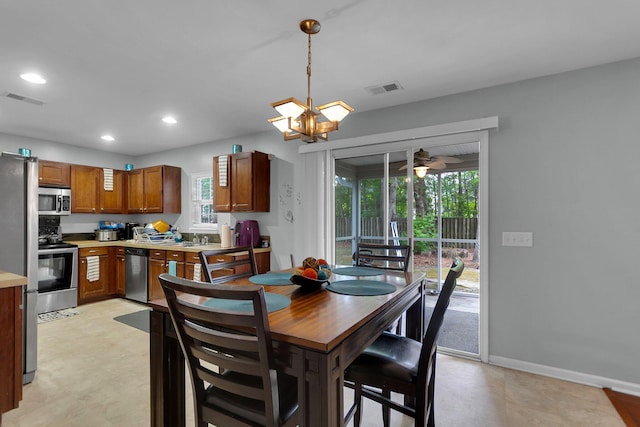 tiled dining area with sink and ceiling fan with notable chandelier