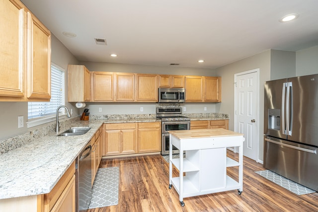 kitchen with dark hardwood / wood-style floors, stainless steel appliances, sink, light stone countertops, and light brown cabinetry