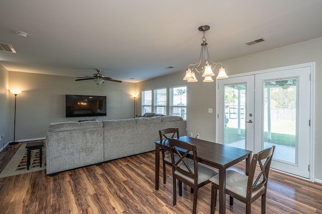 dining area with french doors, dark wood-type flooring, and ceiling fan with notable chandelier