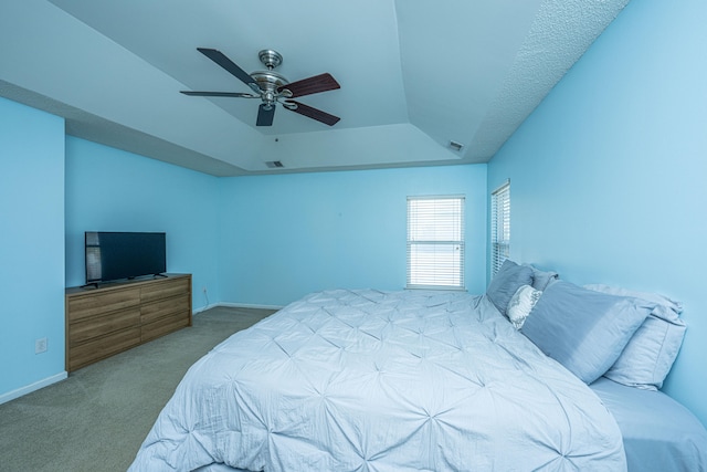 bedroom featuring a raised ceiling, carpet, and ceiling fan