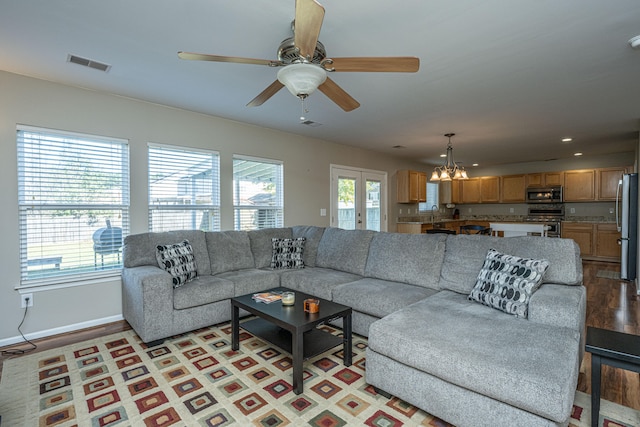 living room with light hardwood / wood-style flooring, a healthy amount of sunlight, and ceiling fan with notable chandelier