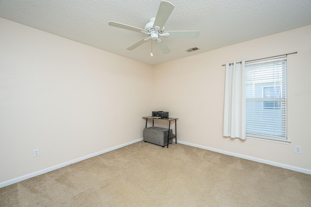 empty room featuring a textured ceiling, light colored carpet, and ceiling fan