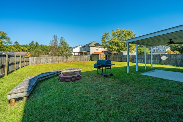 view of yard with a storage shed, a fire pit, and ceiling fan