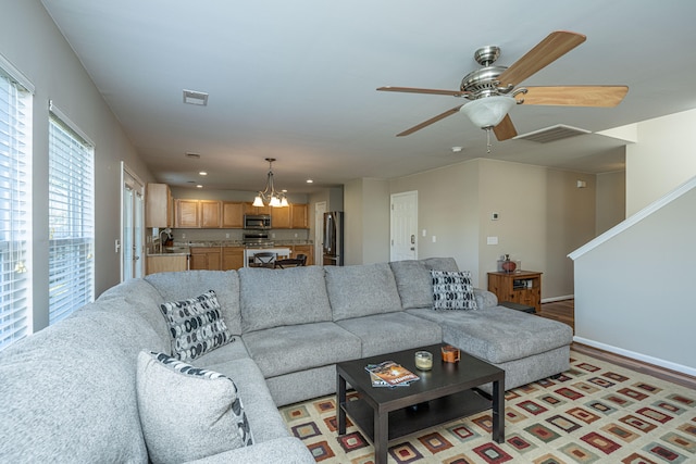 living room with light hardwood / wood-style floors and ceiling fan with notable chandelier