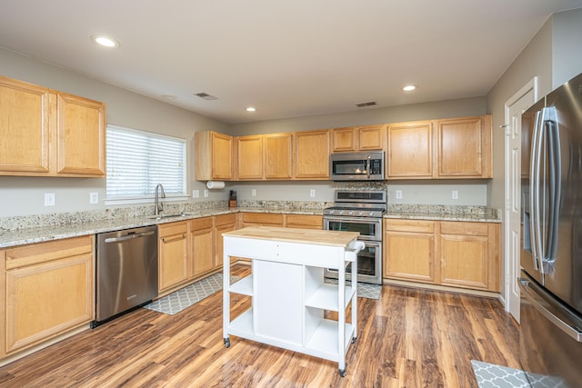 kitchen featuring dark hardwood / wood-style flooring, light stone countertops, light brown cabinetry, sink, and stainless steel appliances