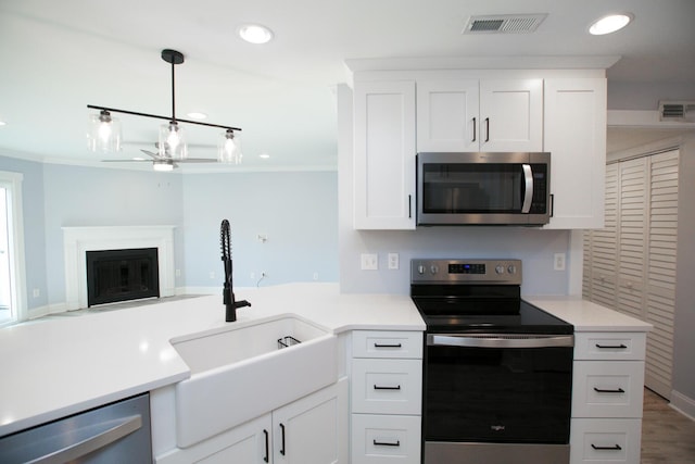 kitchen with a ceiling fan, visible vents, a fireplace with flush hearth, a sink, and appliances with stainless steel finishes