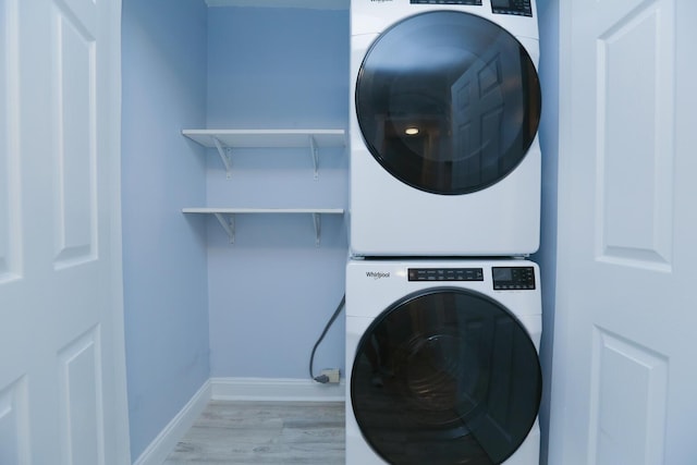 washroom featuring laundry area, light wood-style floors, baseboards, and stacked washer and dryer