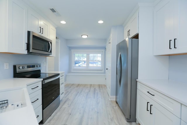 kitchen with visible vents, light wood-style floors, appliances with stainless steel finishes, white cabinets, and light countertops