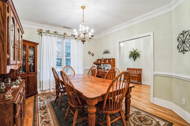 dining space with crown molding, light hardwood / wood-style flooring, and a chandelier