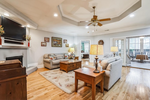 living room featuring light hardwood / wood-style floors, crown molding, and a tray ceiling