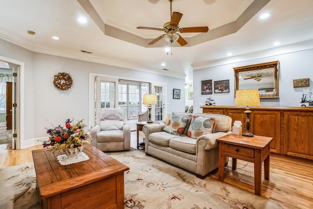 living room with a tray ceiling, light hardwood / wood-style flooring, and ornamental molding