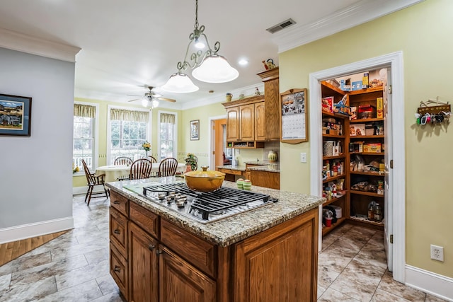 kitchen with ceiling fan, a kitchen island, crown molding, and stainless steel gas cooktop