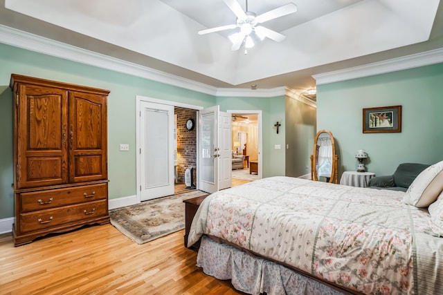 bedroom featuring hardwood / wood-style floors, ceiling fan, ornamental molding, and a tray ceiling