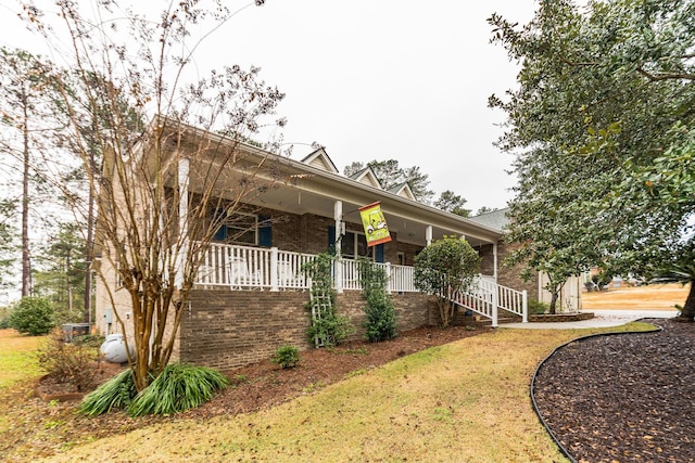 view of side of property featuring a lawn and a porch