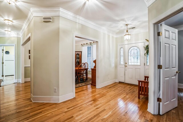 entrance foyer with ornamental molding, a notable chandelier, and hardwood / wood-style flooring