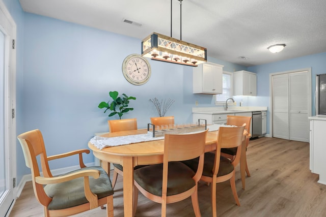 dining room with light hardwood / wood-style flooring, a textured ceiling, and sink