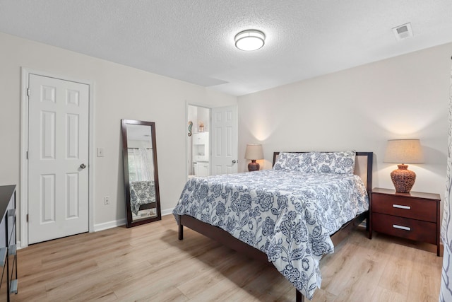 bedroom featuring connected bathroom, a textured ceiling, and light wood-type flooring