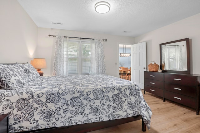 bedroom with a textured ceiling and light hardwood / wood-style floors